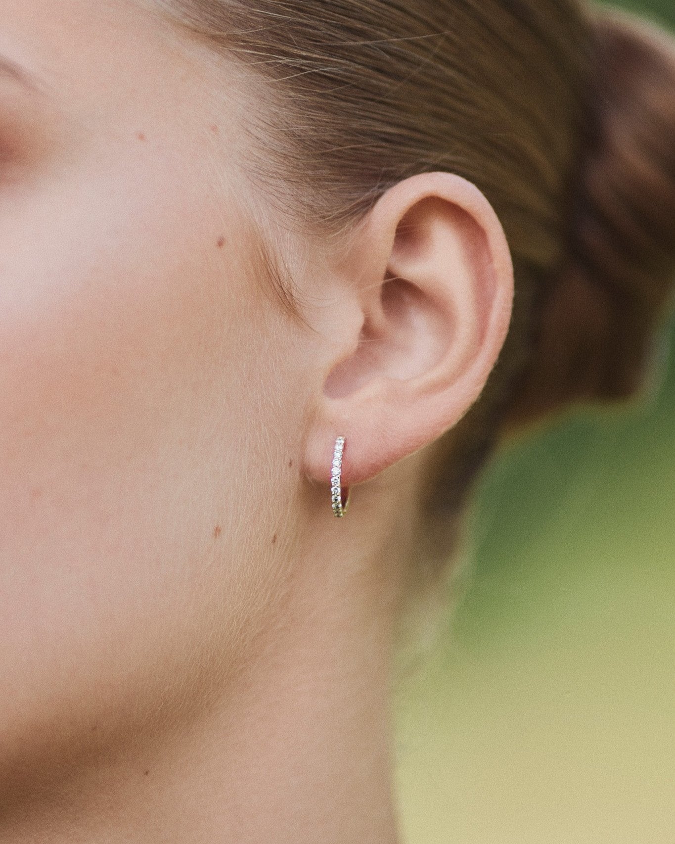 Medium Diamond Hoop white gold earring worn on ear lobe.