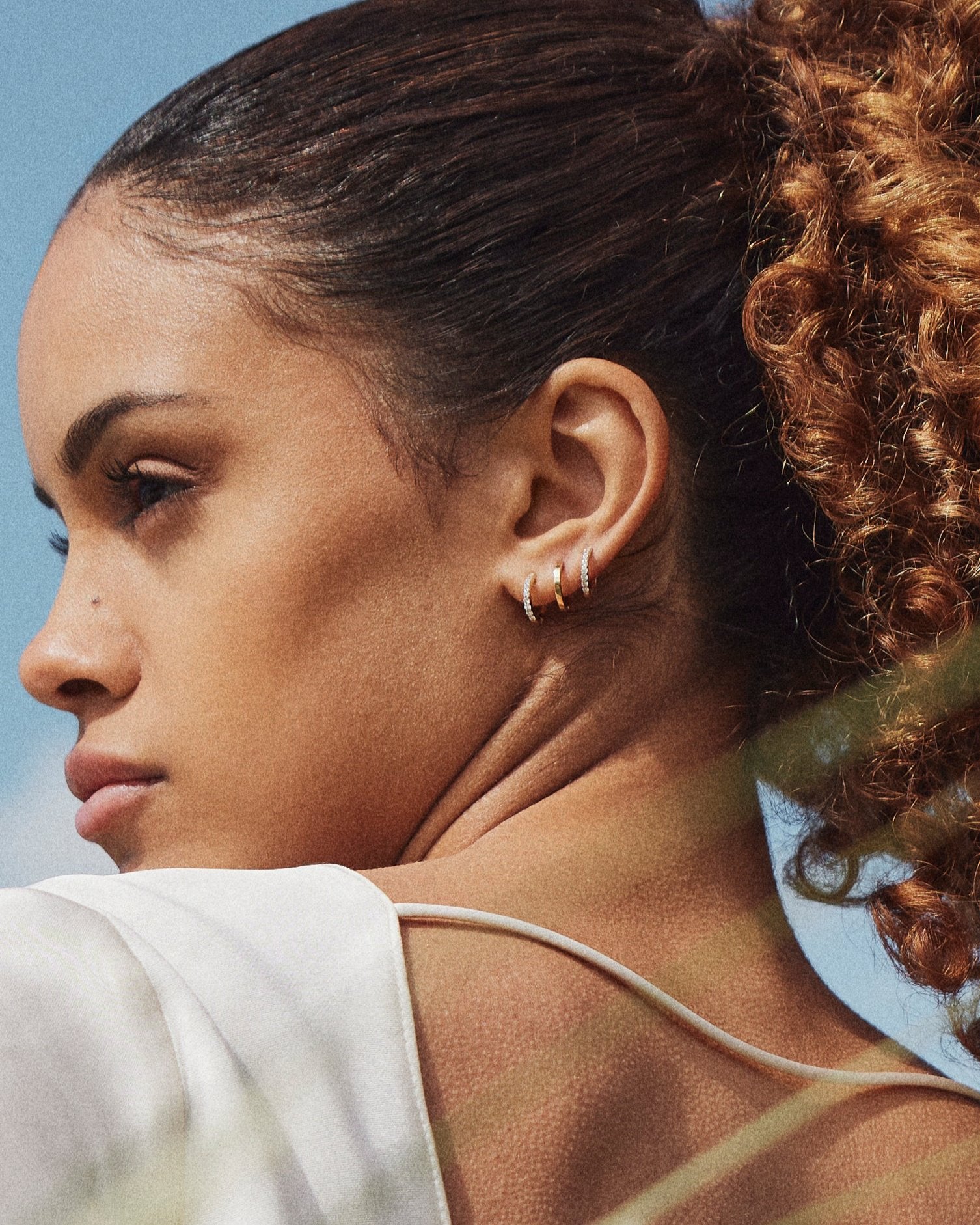 Model wearing the Small Hoop earring in recycled 14K gold with a click-closure design, stacked with the Small Diamond Hoop.